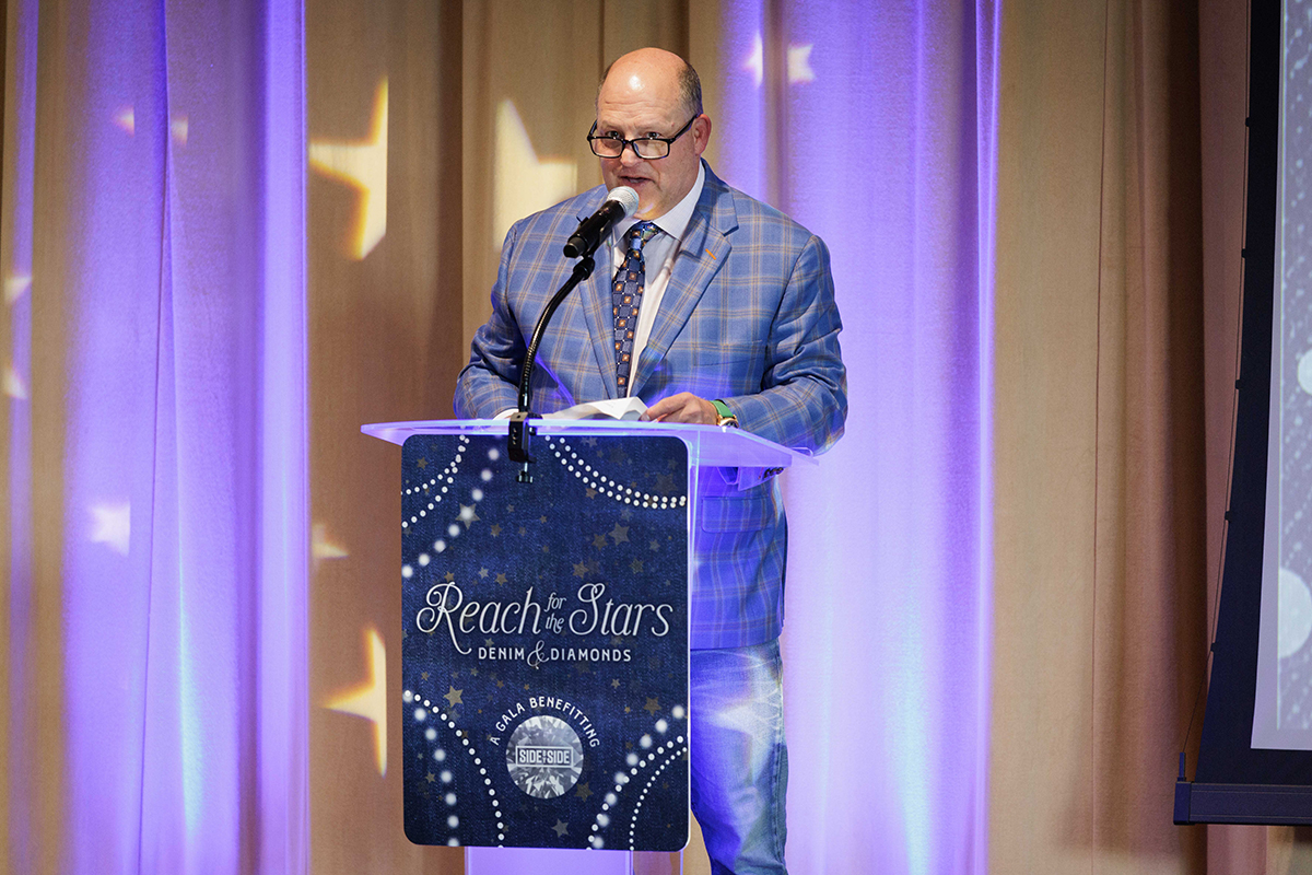 A man in a suit and tie stands confidently at a podium, preparing to address an audience.