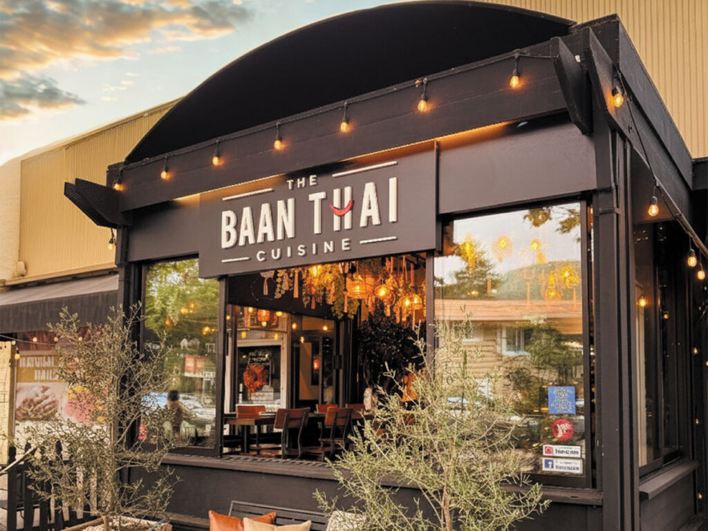 Front entrance of a restaurant featuring a sign that reads "Ban Thai," inviting guests to enter and enjoy Thai cuisine.