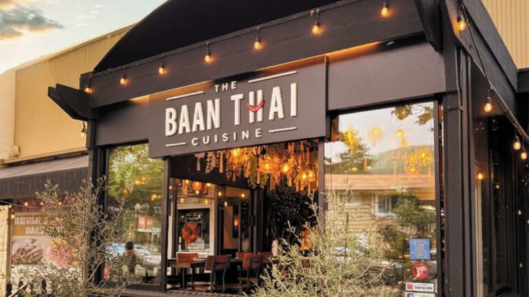 Front entrance of a restaurant featuring a sign that reads "Ban Thai," inviting guests to enter and enjoy Thai cuisine.