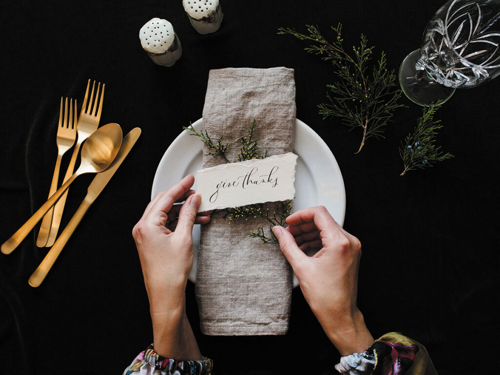 A woman carefully places a thank you note on a decorative plate.