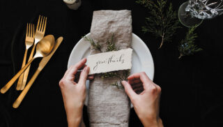 A woman carefully places a thank you note on a decorative plate.