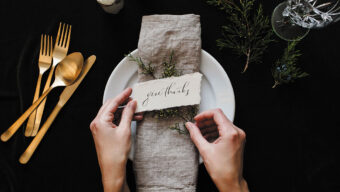 A woman carefully places a thank you note on a decorative plate.