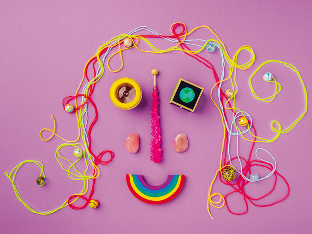 An artistic representation of a face made from bright strings and beads, featuring a playful and colorful design.