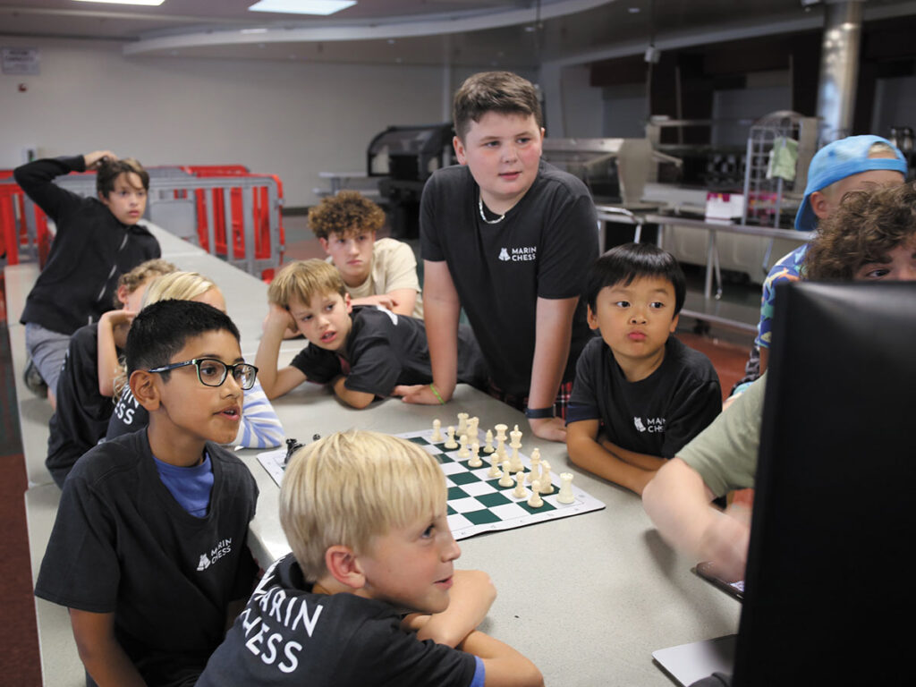 Several kids gathered around a chessboard, concentrating on their moves during an exciting game of chess.