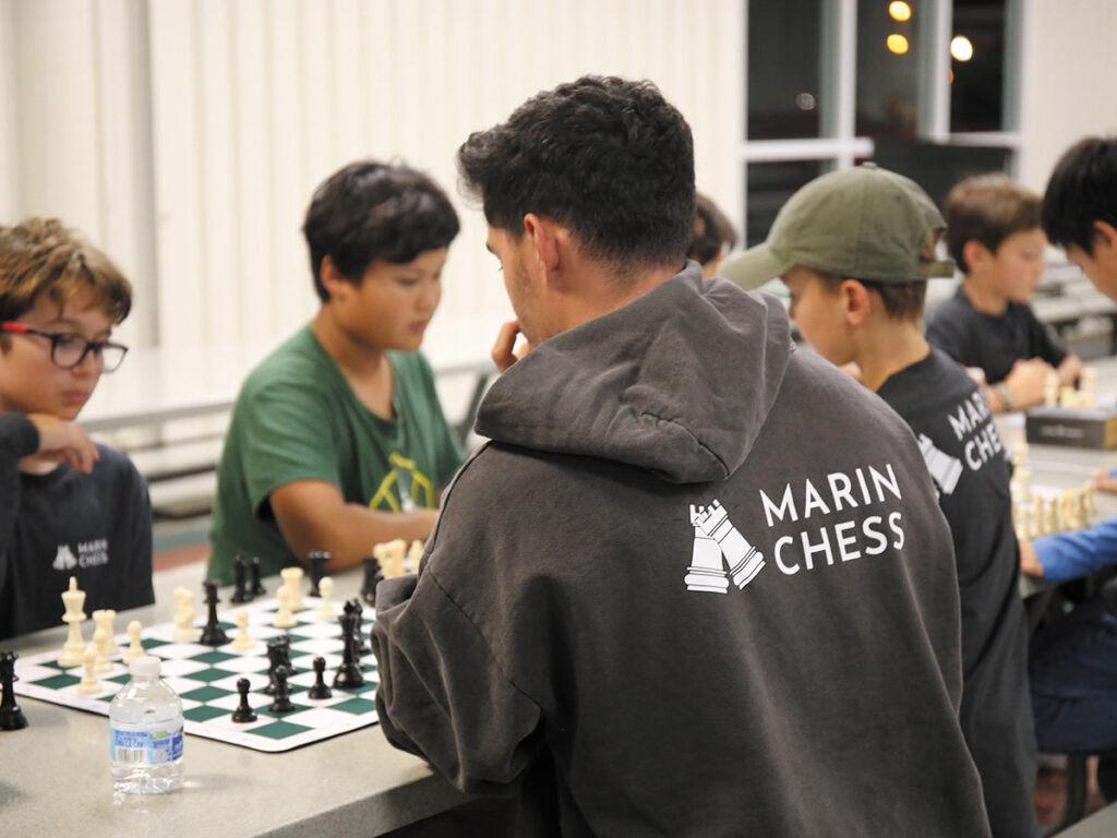 A group of young men engaged in a chess game at a table, focused on their moves and strategies.