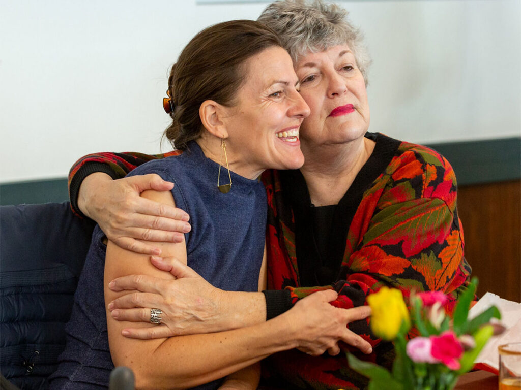 Two women embracing each other in a warm hug, expressing friendship and support.