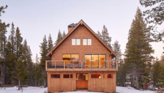 A cozy cabin surrounded by snow, featuring a spacious deck for outdoor relaxation.