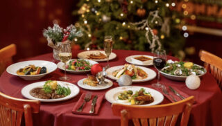 A beautifully arranged Christmas dinner table featuring plates of festive food and holiday decorations.