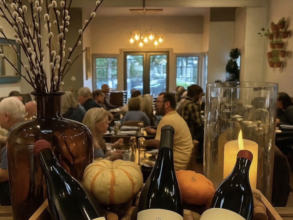 Guests sampling various wines at a rustic winery, surrounded by barrels and vineyard views.