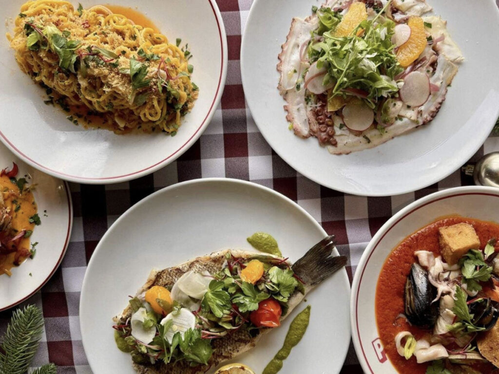 A dining table displaying four plates filled with different dishes, inviting and ready for a meal.
