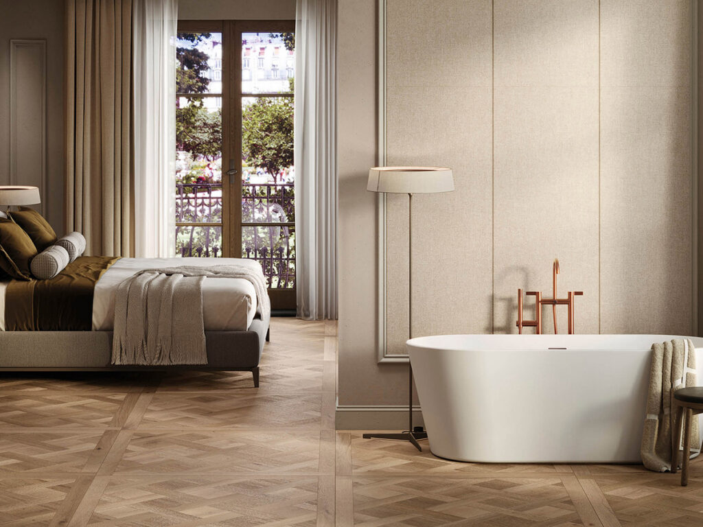 Elegant bedroom with a minimalist aesthetic: a plush bed beside a large window, a freestanding bathtub, warm lighting, and neutral tones throughout.
