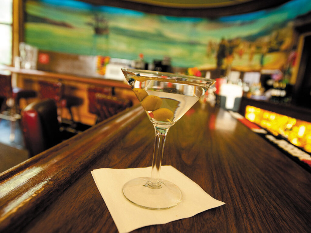 A martini glass filled with a clear beverage, elegantly placed on a wooden table.