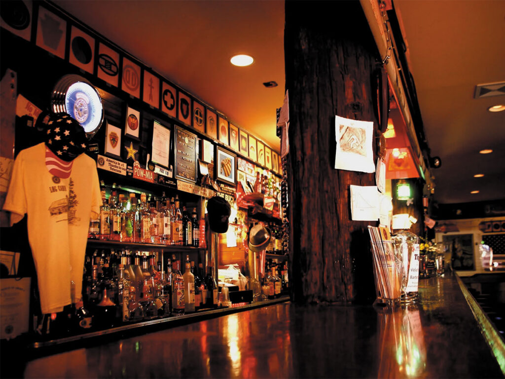 A wooden bar with a polished bar top, featuring stools and a warm, inviting atmosphere.