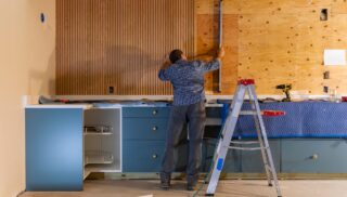 Home improvement Construction blue collar worker building Vertical wood paneling wall in home using level tool