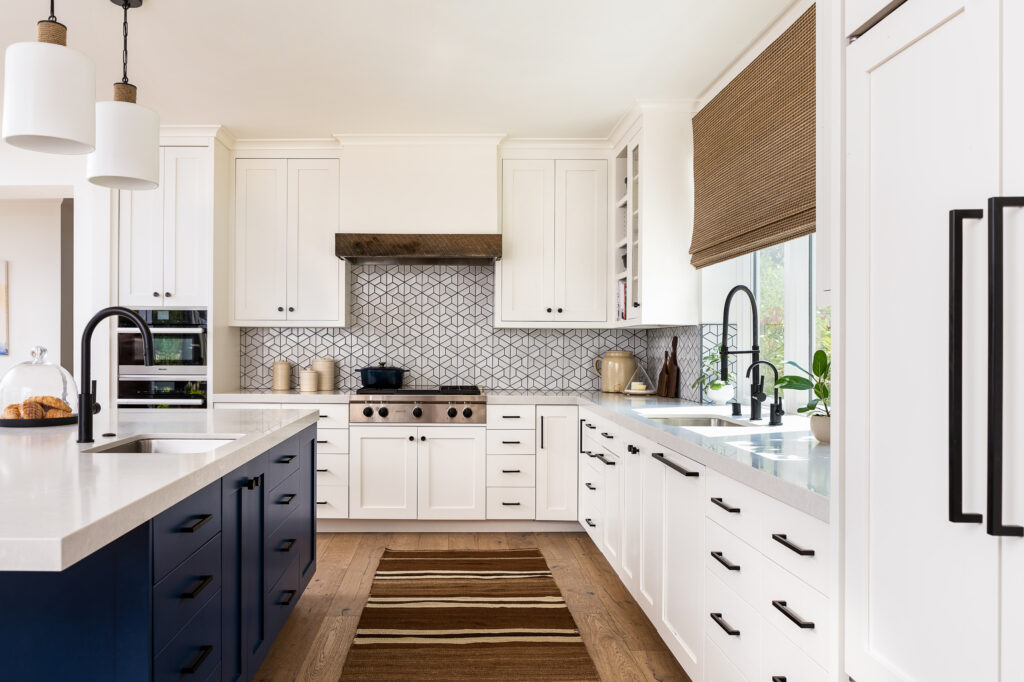 An image of a kitchen with dark blue island cabinets, and white cabinets throughout.