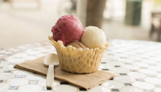 A waffle cup with three scoops of ice cream, vanilla, chocolate and strawberry.
