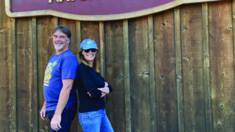 A man and woman are standing in front of a Good Earth sign