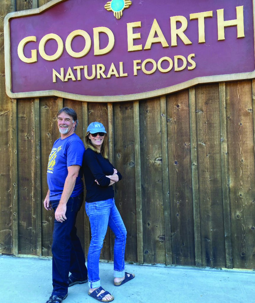 A man and woman are standing in front of a Good Earth sign