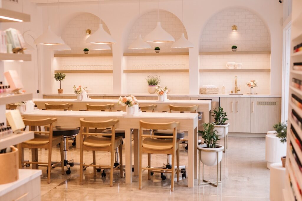 A bright, well-lit nail salon with warm neutral-colored walls and a clean, inviting interior.