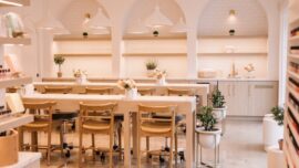 A bright, well-lit nail salon with warm neutral-colored walls and a clean, inviting interior.