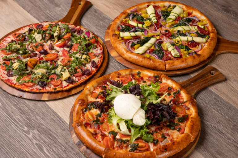 Three pizzas on a wooden table