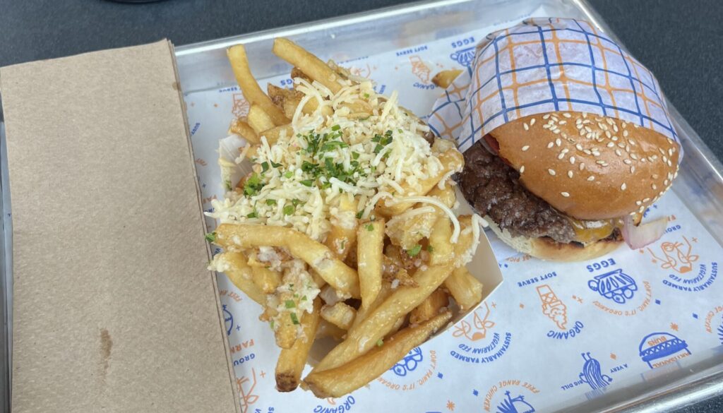 A tray of food including French fries and a hamburger.