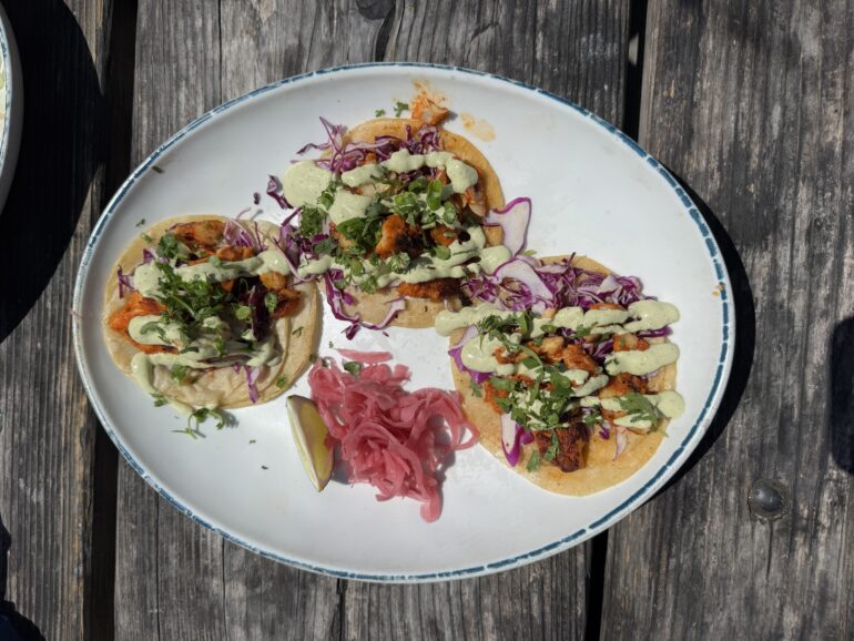 Three fish tacos are on a white plate.