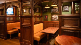 A moody lit corner featuring two enclosed tables and chairs.