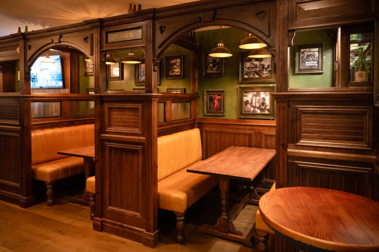 A moody lit corner featuring two enclosed tables and chairs.