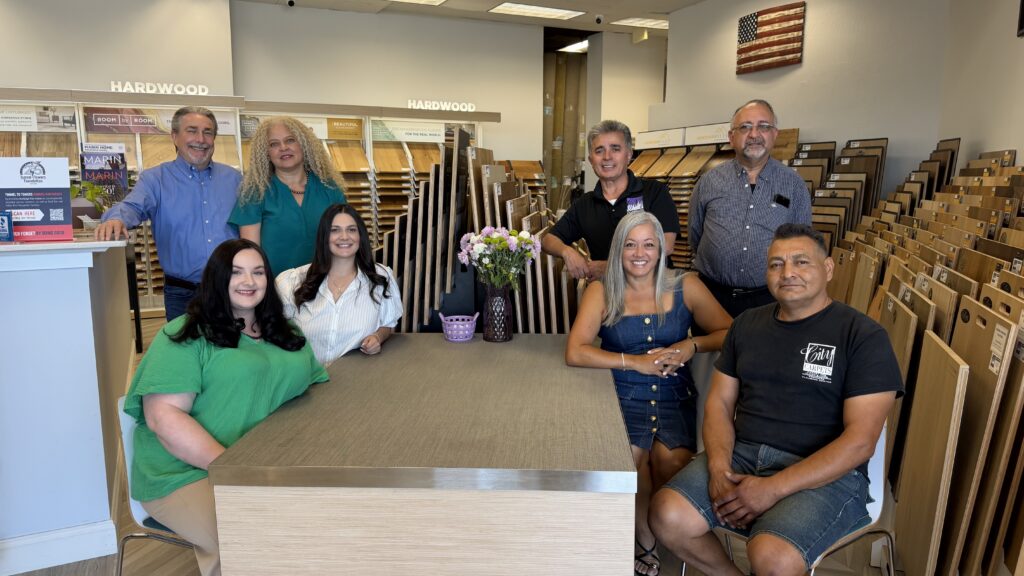 A group of people in a showroom surrounded by floor samples.