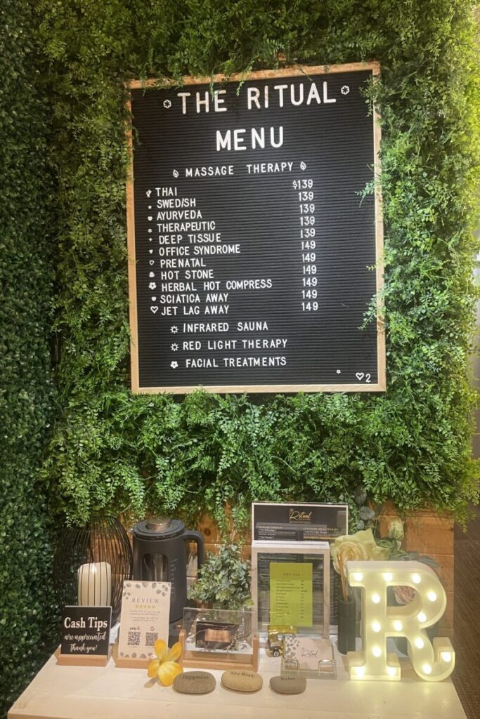 A green grass accent wall displaying a spa menu.services hanging.