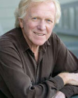 A smiling older man with light-colored hair is leaning on a railing and wearing a dark long-sleeved shirt. The background, hinting at an outdoor setting, subtly features elements of Marin Water's landscape.