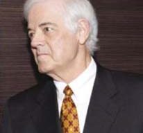 An older man with white hair, dressed in a dark suit, white shirt, and a patterned tie, is pictured gazing to the side as if reminiscing about a memorable dinner against a dark background.