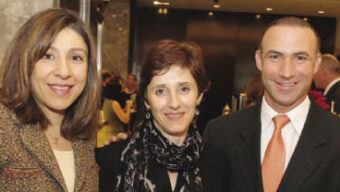 Three people are standing together and smiling in a brightly lit indoor setting at the SF Film Festival. The group consists of two women and one man. The woman on the left has shoulder-length hair and is wearing a brown jacket, the woman in the middle has short hair and is wearing a black scarf, and the man on the right is dressed in a suit and tie.